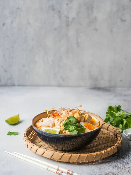Малазийская лапша лапша суп с курицей, креветками и тофу в миске на сером фоне — стоковое фото