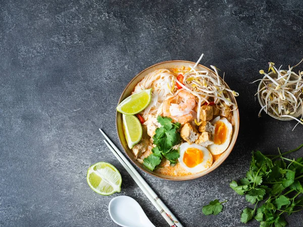 Macarrão malaio sopa de laksa com frango, camarão e tofu em uma tigela no fundo escuro — Fotografia de Stock