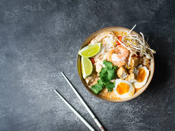 Macarrão malaio sopa de laksa com frango, camarão e tofu em uma tigela no fundo escuro — Fotografia de Stock