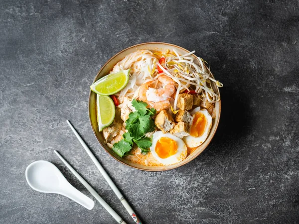 Суп з лакси малайзійської локшини з куркою, креветкою і тофу в мисці на темному тлі — стокове фото