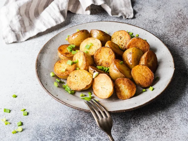 Cuñas de patata asadas fritas con cebolletas en placa vintage sobre fondo gris — Foto de Stock