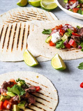 Sebzeli tortilla ve biftek dilimleri. Avokadolar, domatesler, kırmızı soğanlar ve kişniş ve limon suyu ile tortilla. Meksika yemeği.