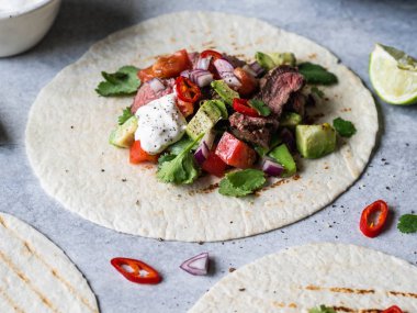 Sebzeli tortilla ve biftek dilimleri. Avokadolar, domatesler, kırmızı soğanlar ve kişniş ve limon suyu ile tortilla. Meksika yemeği.