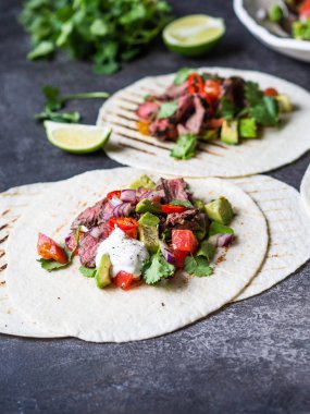 Sebzeli tortilla ve biftek dilimleri. Avokadolar, domatesler, kırmızı soğanlar ve kişniş ve limon suyu ile tortilla. Meksika yemeği.