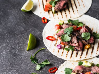 Sebzeli tortilla ve biftek dilimleri. Avokadolar, domatesler, kırmızı soğanlar ve kişniş ve limon suyu ile tortilla. Meksika yemeği.