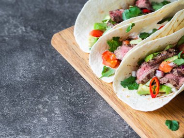 Sebzeli tortilla ve biftek dilimleri. Avokadolar, domatesler, kırmızı soğanlar ve kişniş ve limon suyu ile tortilla. Meksika yemeği.