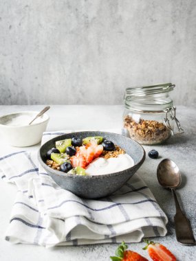 Lezzetli sağlıklı kahvaltı - yoğurt ve böğürtlenli granola, kasede yoğurt ve masada cam kavanozda granola..