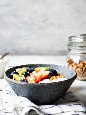 Lezzetli sağlıklı kahvaltı. Yoğurt ve böğürtlenli tahıl, kasede yoğurt ve masada cam kavanozda granola. Boşluğu kopyala.