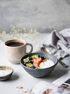 Lezzetli kahvaltı, bir fincan kahve, kabın içinde hindistan cevizi yoğurt, böğürtlen ve açık dergi. Boşluğu kopyala.