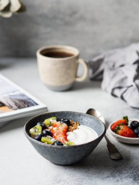 Lezzetli kahvaltı, bir fincan kahve ve yoğurt, böğürtlen ve açık dergi. Boşluğu kopyala.