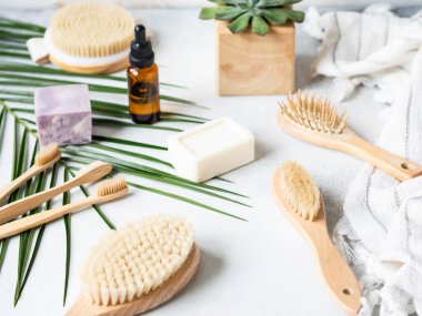 Farklı vücut fırçaları, sünger taşları, bambu diş fırçası, beyaz havlu ve gri arkaplanda bir kalıp sabun. Sıfır atık. Çevre dostu banyo seti. Boşluğu kopyala