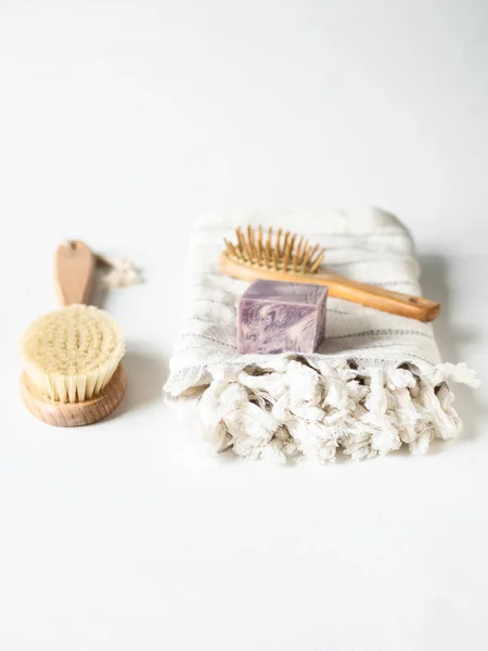 Body brush with wooden handle, pumice, white towel and a piece of soap on a white background. Zero waste concept. Eco-friendly bath set. copy space