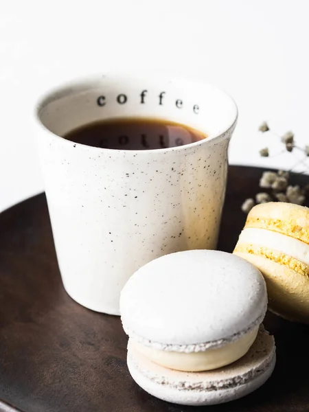 Deux macarons pastel avec tasse en céramique blanche de café noir sur plaque de bois sur fond blanc — Photo