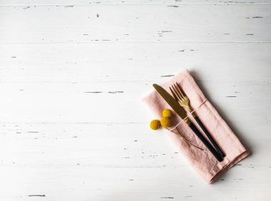 Pembe peçeteli, sarı çiçekli ve beyaz ahşap masadaki aletli taşralı romantik masa. Üst görünüm.