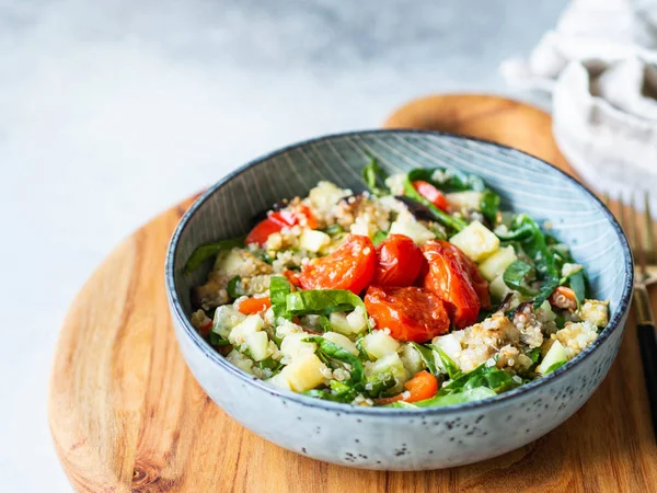 Kinoa salatası, fırında sebze, ıspanak ve mavi tabakta çiğ salatalık. — Stok fotoğraf