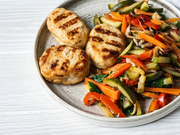 Turkey cutlets grill, vegetables steer fry on a plate on wood board table. Copy space