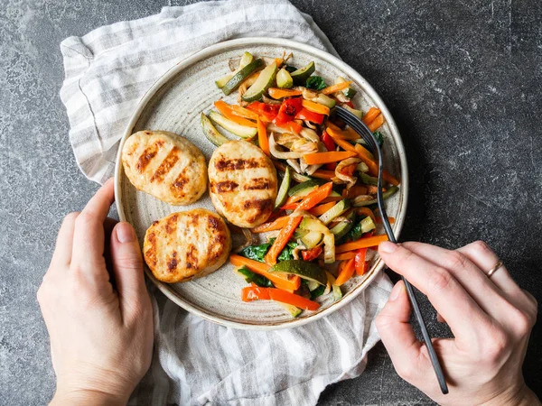 Turkey cutlets grill, vegetables steer fry and hands on a plate on the table. Top view