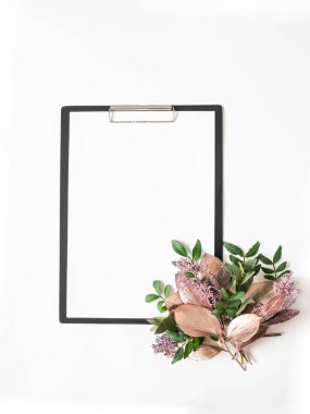 Siyah pano, yazı için beyaz kağıt beyaz arka planda çeşitli boyalı yapraklar ve yeşil yapraklardan oluşan yaratıcı bir buket. Üst Manzara. Boşluğu kopyala