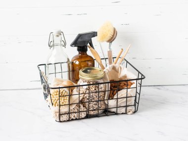 Sıfır atık. Çevre dostu mutfak seti. Yiyecek, fırça, ahşap eşyalar, çantalar, şişe ve kavanoz siyah metal bir sepetin içinde. Boşluğu kopyala