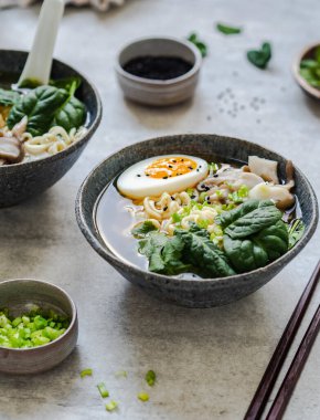 Mantarlı vejetaryen Miso Ramen, çiğ ıspanak ve gri masada kaynamış yumurta.
