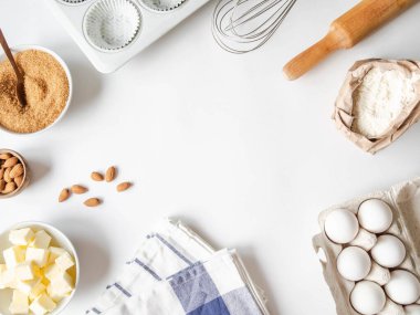 Çeşitli fırın malzemelerinin çerçevesi - un, yumurta, şeker, tereyağı, fındık, mutfak gereçleri ve beyaz arka planda kek pişirme kabı. Üst Manzara. Boşluğu kopyala