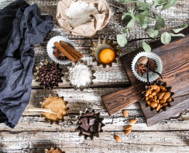 Fırın malzemeleri: un, esmer şeker, yumurta, kakao, badem, sade ahşap zemin üzerinde koyu çikolata ve baharatlar. Üst Manzara. Boşluğu kopyala