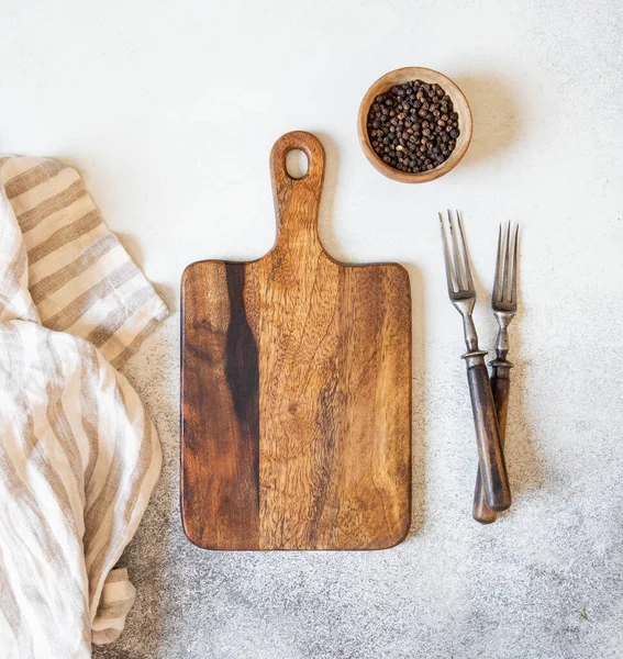 Wood cutting board mock up, spices in a wooden bowl and two vintage forks on gray background. Top view. Copy space