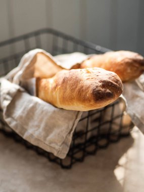 Masadaki siyah metal sepetin içinde iki taze ev yapımı Fransız ekmeği.