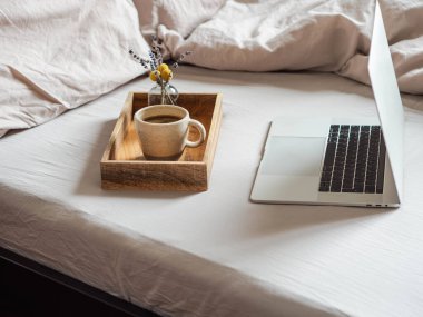 Laptop and coffee on the bed in the bedroom. Work from home or a comfortable pastime online. Stay home, quarantine. Work at home concept. clipart