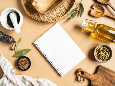 Mutfak dairesi mutfak metni ve çeşitli kuru baharatlar, ahşap mutfak aletleri, bej arka planda cam şişedeki zeytinyağı için açık defter ile yatıyordu. Üst Manzara. Boşluğu kopyala