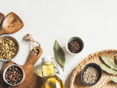 Küçük kaseler dolusu kuru baharatlar, ahşap mutfak aletleri ve arka planda cam şişedeki zeytinyağı. Üst Manzara. Boşluğu kopyala