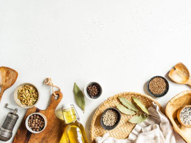 Küçük kaseler dolusu kuru baharatlar, ahşap mutfak aletleri ve arka planda cam şişedeki zeytinyağı. Üst Manzara. Boşluğu kopyala