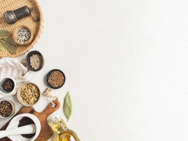 Küçük kaseler dolusu kuru baharatlar, ahşap mutfak aletleri ve arka planda cam şişedeki zeytinyağı. Üst Manzara. Boşluğu kopyala