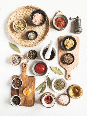 Hafif arka planda çeşitli kuru baharatlar ve soslar. Dijon hardallı, zeytinyağlı, ketçaplı, kapari ve baharatlı küçük kaseler. Üst görünüm