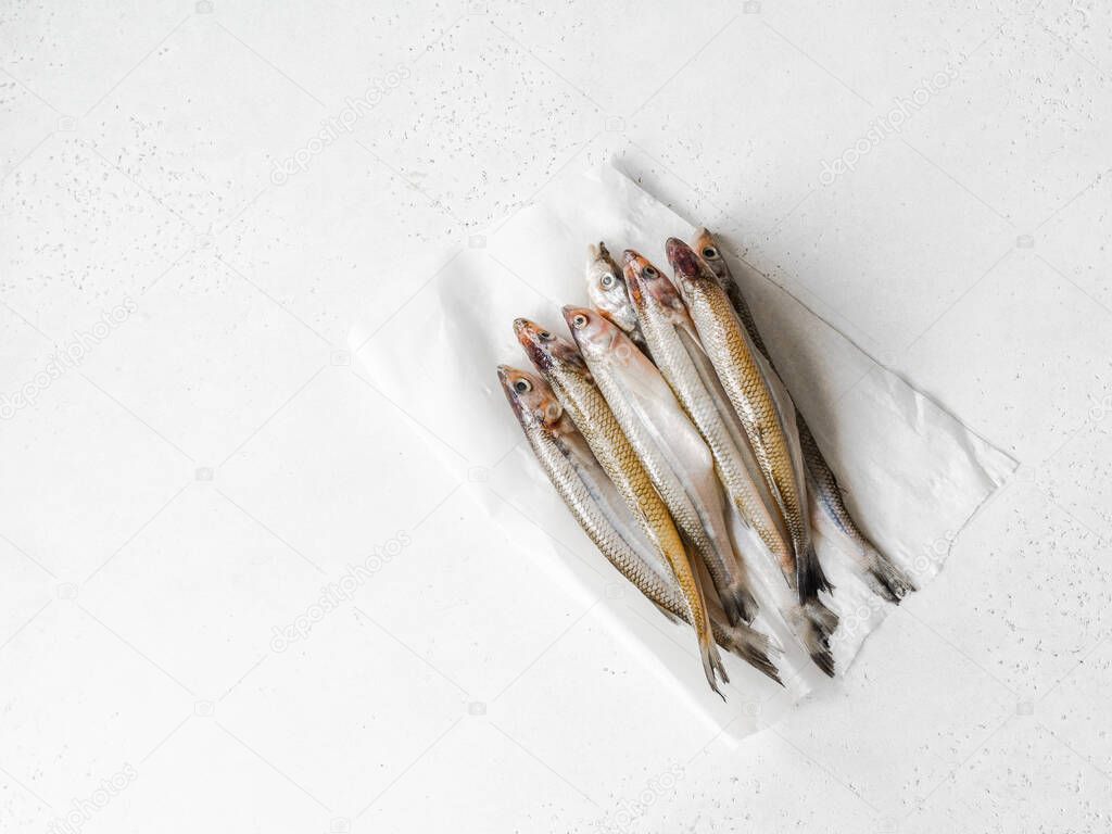 Fresh raw smelt fish on paper on a wind background. Top view