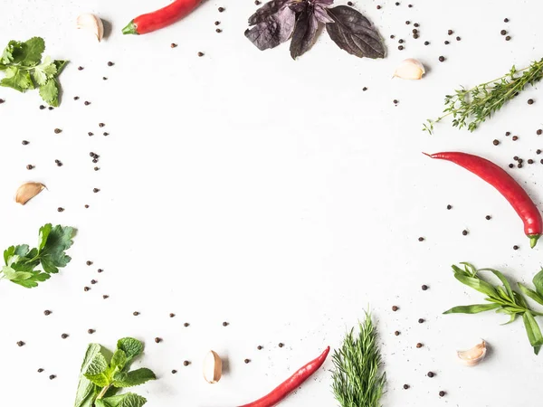 Frame of fresh raw herbs - mint, thyme, dill, parsley, basil and tarragon, garlic, red pepper, spices on a textured background. Top view. Copy space