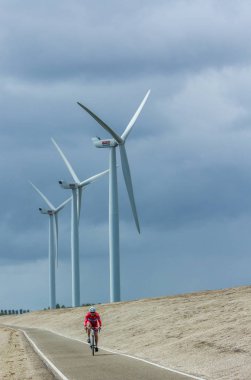 Hollandalı bisikletçi bir dike yakın Rüzgar türbinleri üzerinde yarış