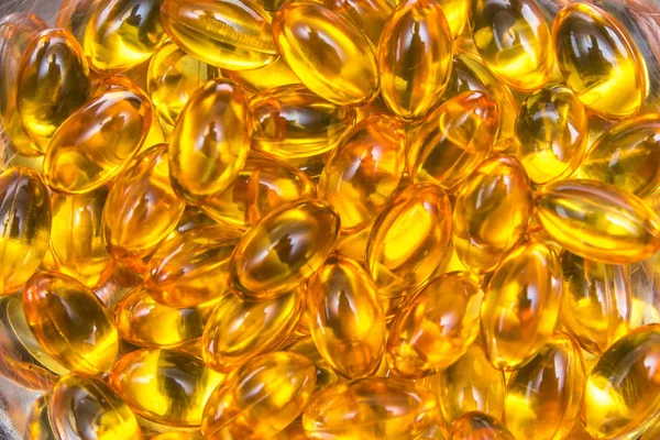 Closeup fish oil capsules in golden hue — Stock Photo, Image