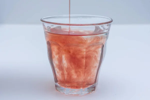 Refrescante extrato de suco de frutas derramado em vidro de água — Fotografia de Stock