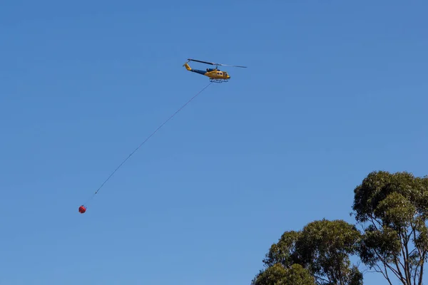 Helikopter uitvoering emmer water blussen van bosbranden — Stockfoto