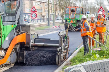 Laan van meerdervoort, The Hague, the Netherlands - 31 march 2017: road work team laying blacktop to resurface new road clipart