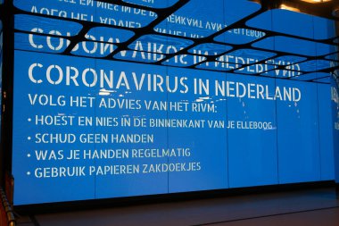 Amsterdam, Hollanda - 18 Mart 2020: Hollanda tren istasyonundaki elektronik billboardlarda koronavirüs uyarısı