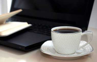 laptop ve kahve fincan üzerinde boş bir not defteri. 