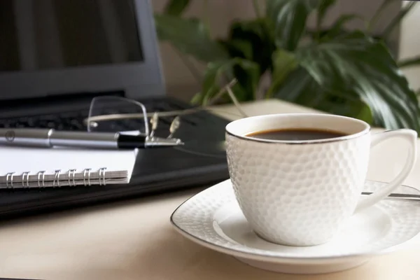 Bloc de notas en blanco sobre el ordenador portátil y la taza de café . — Foto de Stock