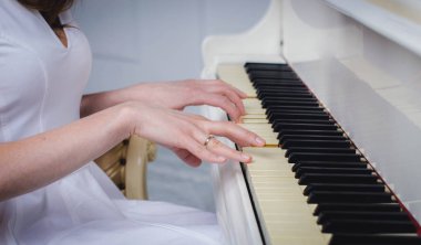üzerinde beyaz bir piyano çalan kız