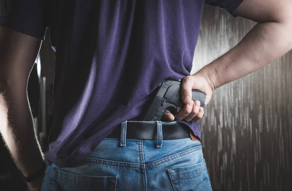 Svart pistol i handen bakom hans rygg — Stockfoto