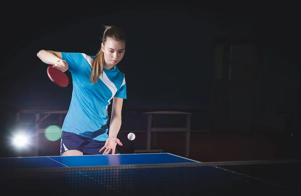 a girl plays table tennis, takes the ball