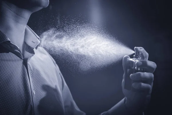 Siyah arka plan üzerine parfüm kullanan yakışıklı adam