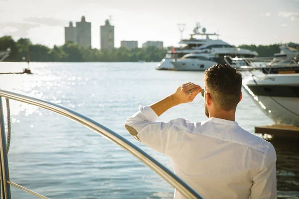 Vista posteriore di un potente uomo d'affari in piedi da barche a vela e yacht costosi in una città costiera, contemplando la vista . — Foto Stock