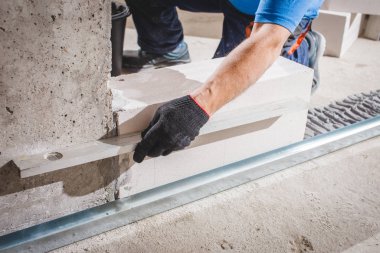 Usta tutkal ve mala kullanarak duvarı gaz bloklarıyla gözlüyor.